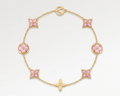 Gold bracelet with pink flower-shaped links on a light gray background