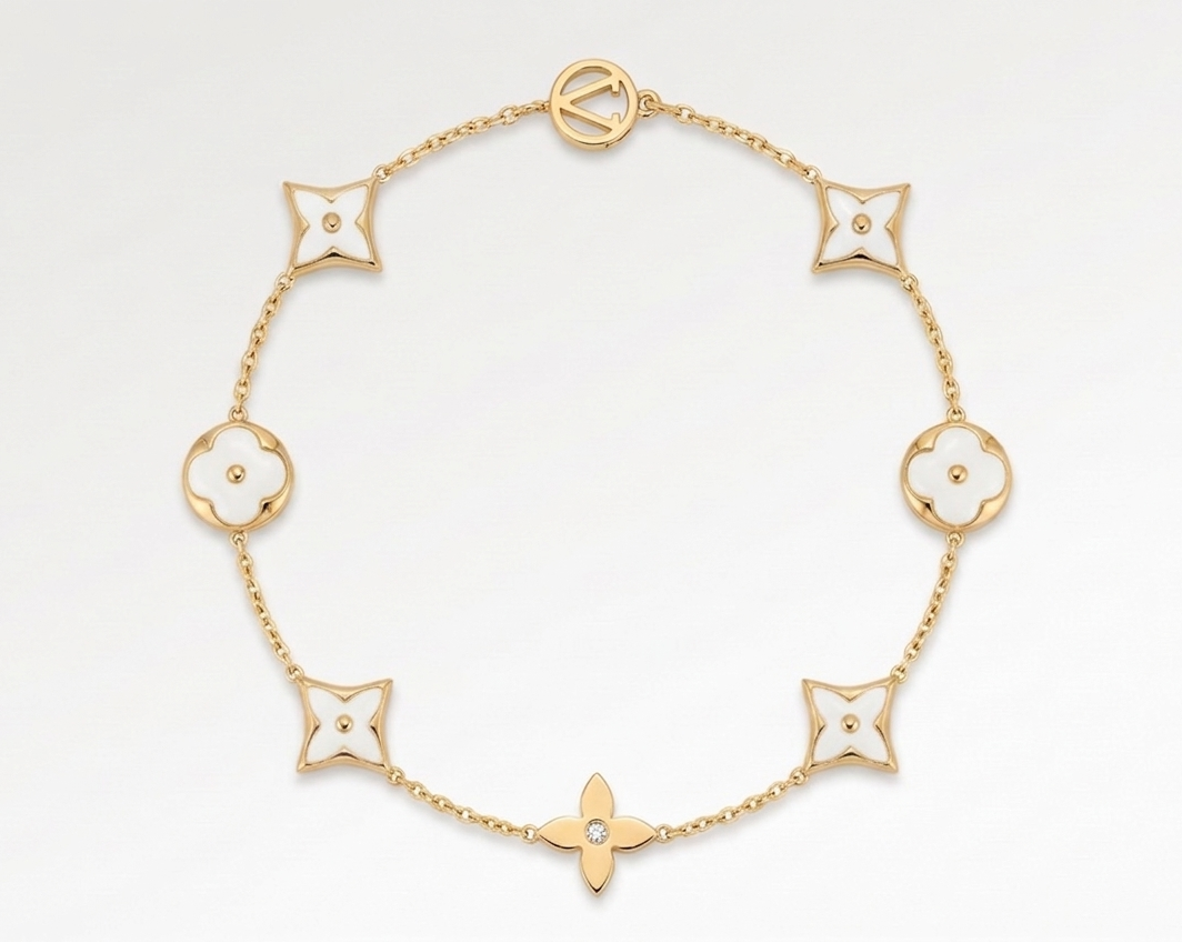 Gold bracelet with white flower-shaped links on a white background